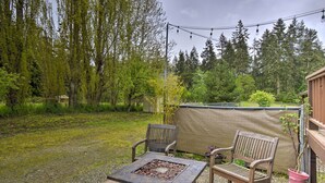 An outdoor patio with two wooden chairs, a square table, and a fire pit.