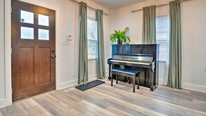 A room with a piano, a door, and curtains. - Indianapolis Vacation Home: 3 Mi to Dtwn! (Indianapolis)
