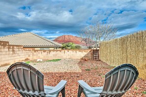 A backyard with two Adirondack chairs, a wooden fence, and a mountain in the background. - Ivins Studio w/ Yard + Mountain Views! (Ivins)