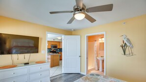 Un dormitorio con cama, cómoda, ventilador de techo y vista a la cocina.