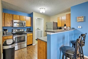 A compact kitchen with wooden cabinets, stainless steel appliances, and a small bar area. - Lafayette House - 7 Mi. to Purdue & Downtown! (Lafayette)