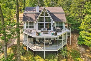 A large, multi-level house with a wrap-around deck, multiple windows, and outdoor seating areas. - Luxurious Waterfront Home on Pickwick Lake! (Iuka)