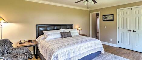 A bedroom with a bed, nightstand, chair, and a ceiling fan.