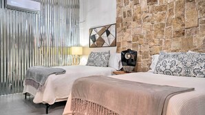 A hotel room with two beds, a stone wall, a geometric artwork, and an air conditioning unit. - Laredo Vacation Rental - Minutes From Attractions! (Laredo)
