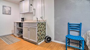 A small kitchenette with white cabinets, a microwave, and a coffee maker. There is a blue chair and a small rug on the floor. - Vacation Rental Near Boyd Lake, Colorado! (Loveland)