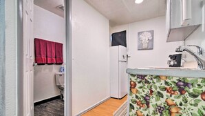 A compact kitchen with a refrigerator, sink, and a fruit-patterned counter. - Vacation Rental Near Boyd Lake, Colorado! (Loveland)