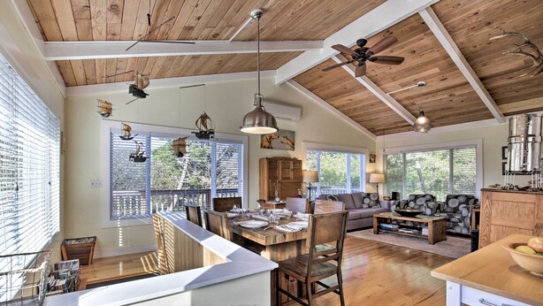 A spacious living area with a wooden ceiling, large windows, and a dining area with a long table and chairs. - Private Rockaway Beach Retreat: 2 Blocks to Ocean! (Rockaway Beach)