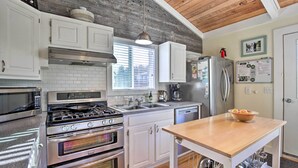 A kitchen with white cabinets, stainless steel appliances, a wooden ceiling, and a window with blinds. - Private Rockaway Beach Retreat: 2 Blocks to Ocean! (Rockaway Beach)