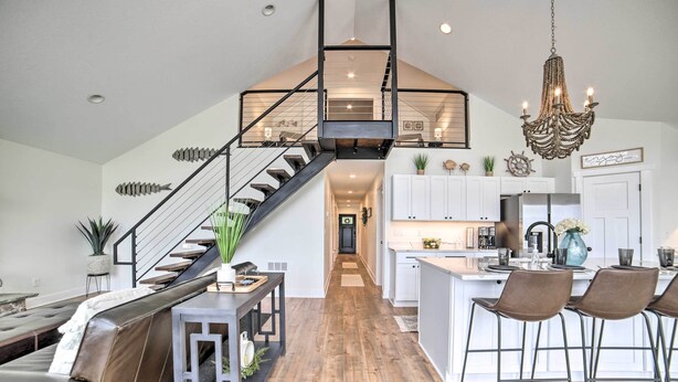 A modern kitchen with a central island, bar stools, and a staircase leading to an upper level. - Newly Built Gilletts Lake Gem: Dock & Hot Tub (Jackson)