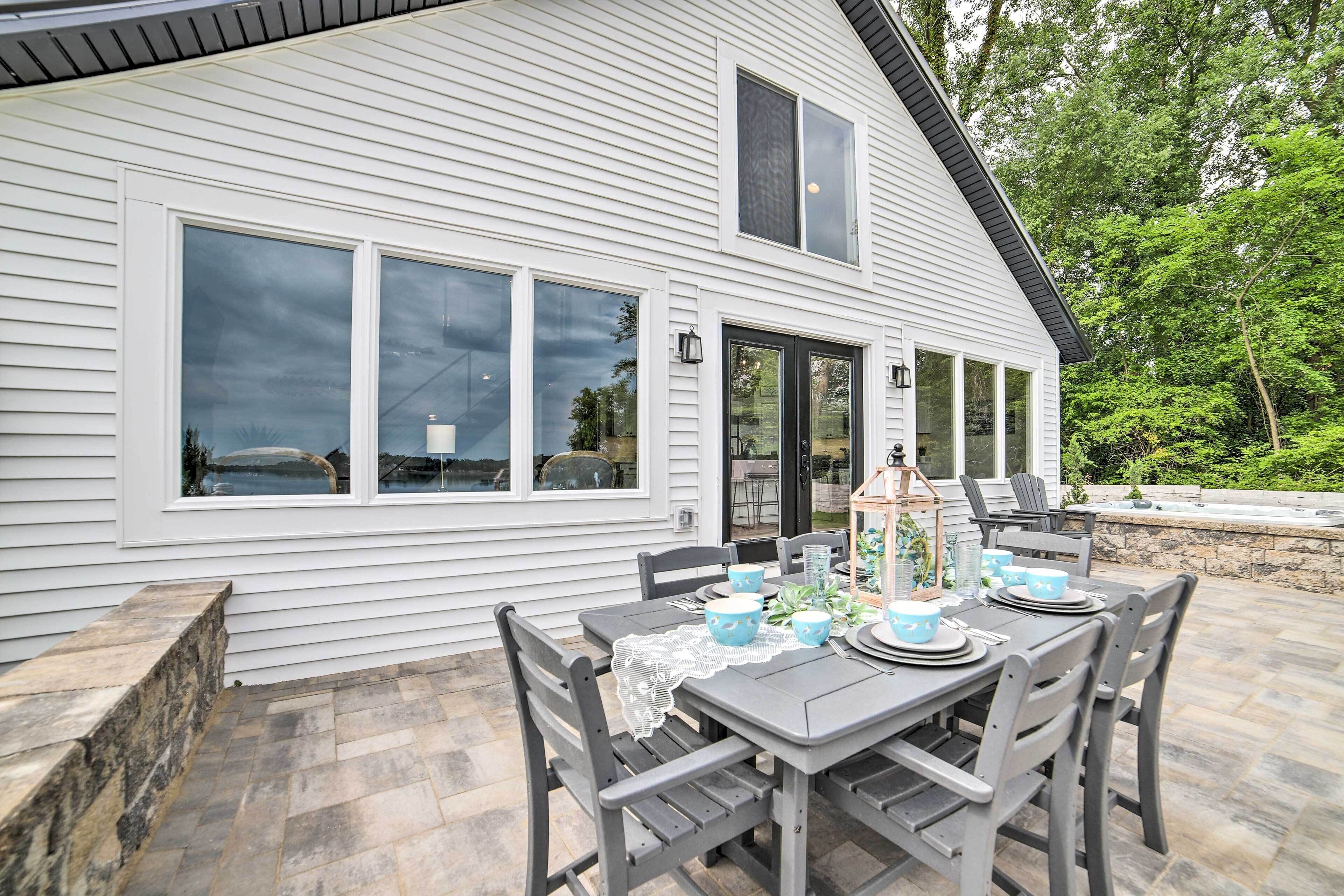 A patio with a table set for dining, surrounded by chairs.