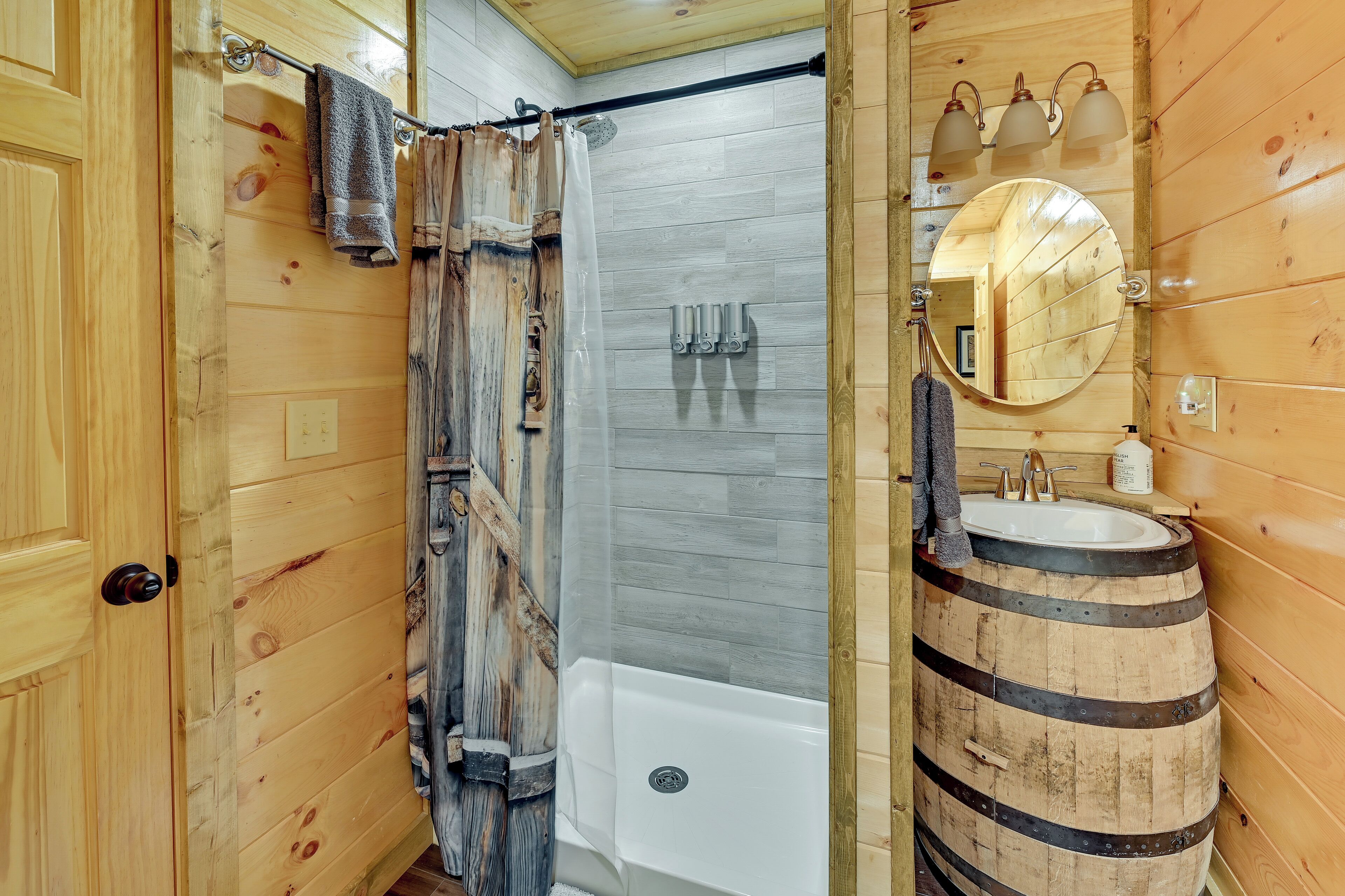Un bagno in legno con una vasca, una tenda da doccia, un lavabo con un catino in legno e uno specchio.