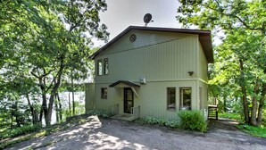 A two-story house with a satellite dish, a front porch, and a driveway leading to the entrance. - Waupaca Lakefront Home w/ Pool Table & Dock! (Waupaca)