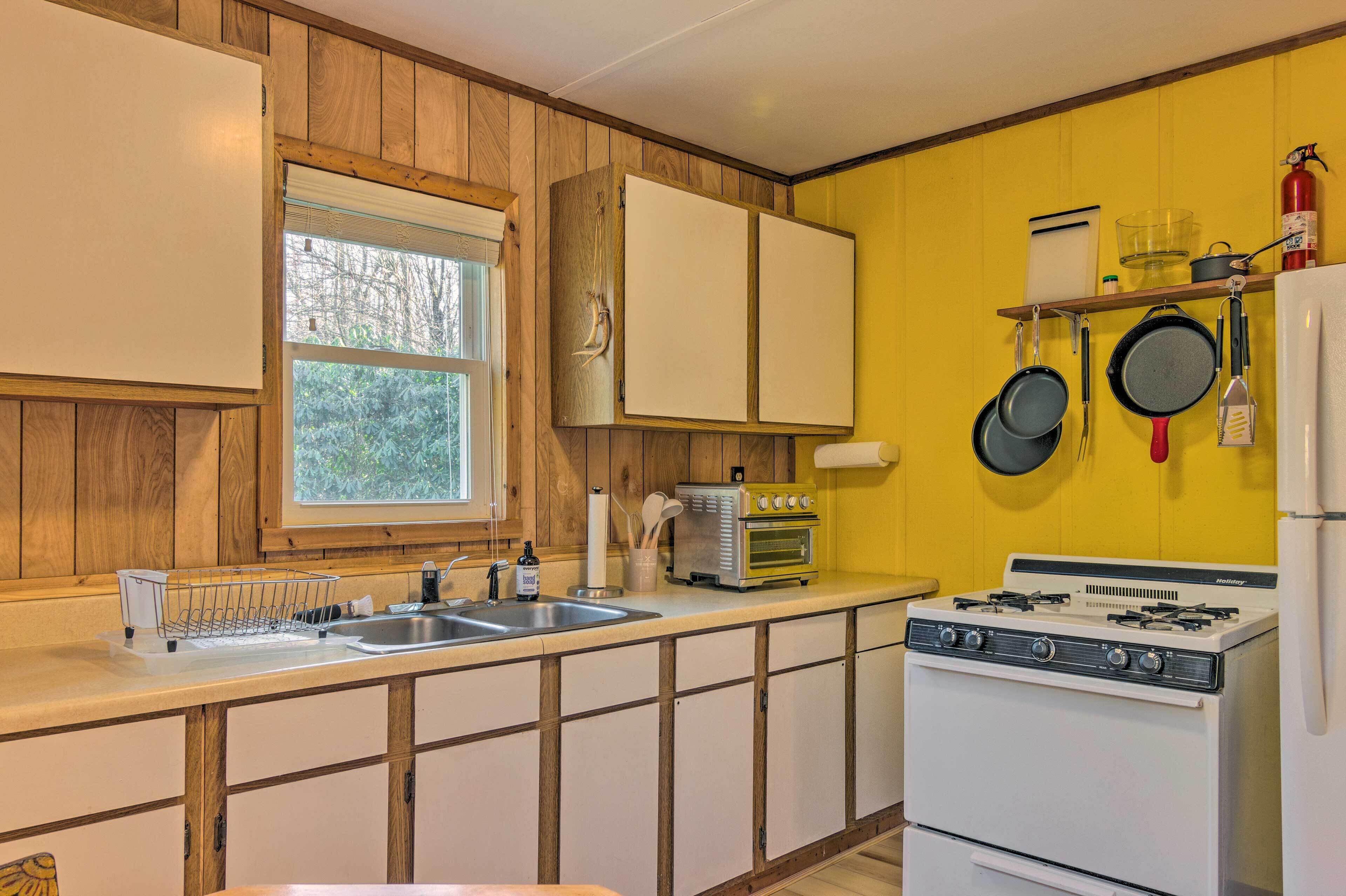 A kitchen with wooden cabinets, a stove, a sink, and a window.