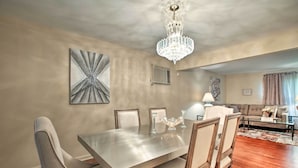 A dining area with a rectangular table, six chairs, a chandelier, and a large abstract painting on the wall. - Home w/ Yard & Patio ~ 30 Mi to Downtown Chicago (Matteson)