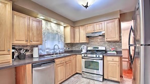 A modern kitchen with wooden cabinets, stainless steel appliances, and a tiled backsplash. - Home w/ Yard & Patio ~ 30 Mi to Downtown Chicago (Matteson)