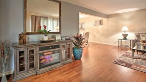 A living room with a fireplace, a large mirror, and a blue vase with plants. - Home w/ Yard & Patio ~ 30 Mi to Downtown Chicago (Matteson)