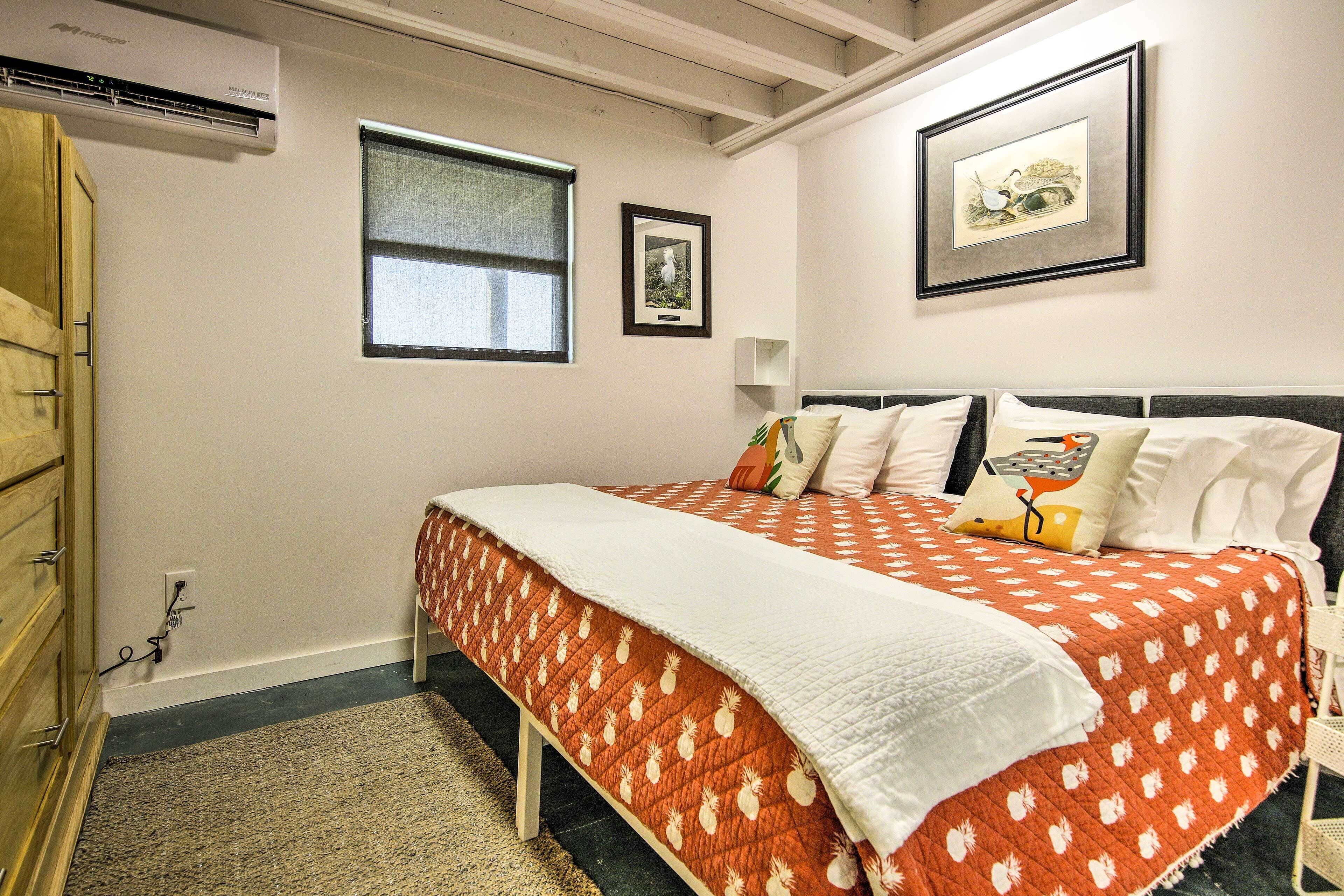 Een slaapkamer met een bed, een raam, een wandairconditioner en een lijst met een afbeelding.