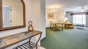Une chambre d’hôtel comprenant un coin repas, un grand miroir, un élément décoratif en bois et un ventilateur de plafond.