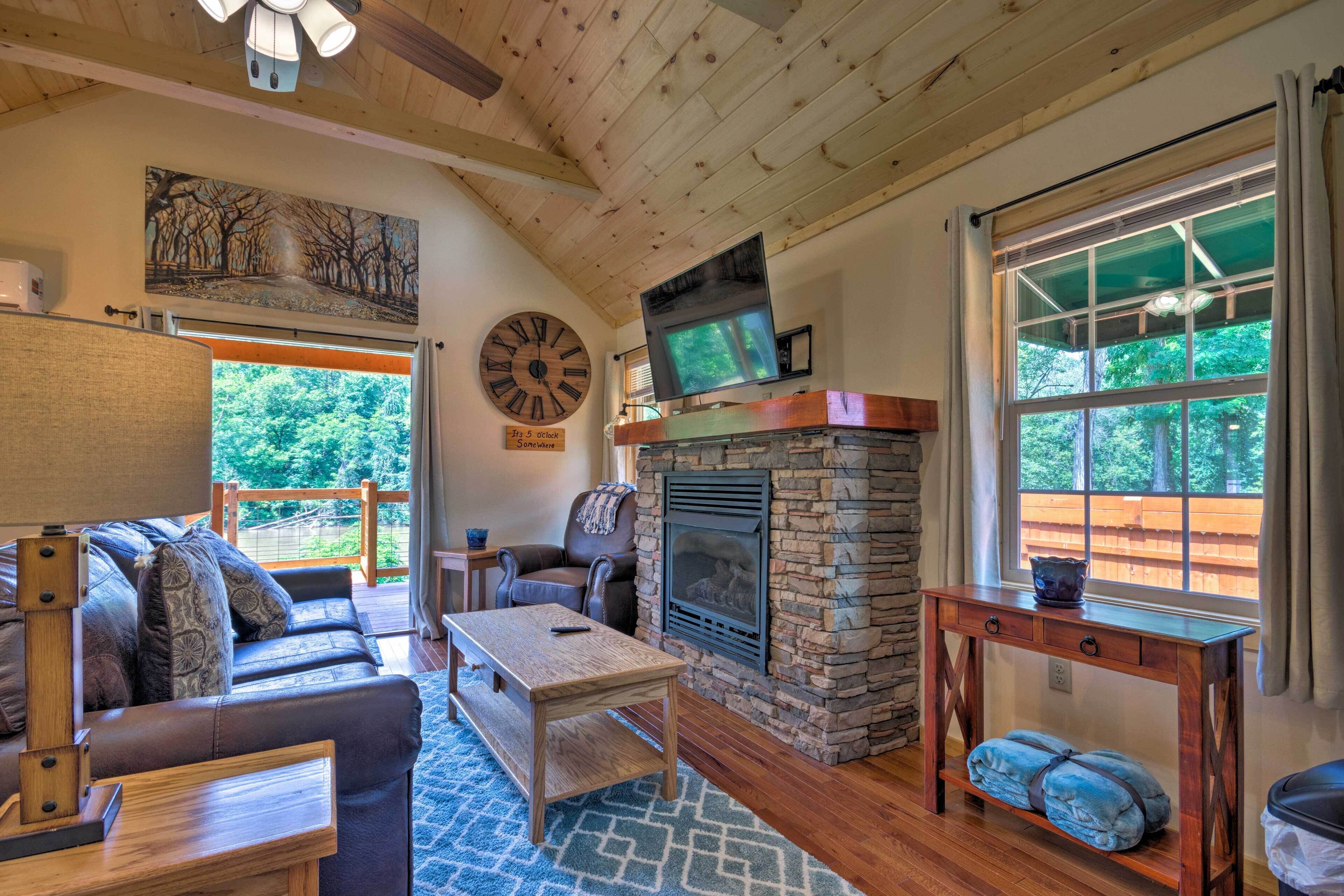 A cozy living room with a stone fireplace, a large clock, and a comfortable seating area.