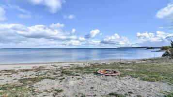 A beach with a fire pit and a view of the water.