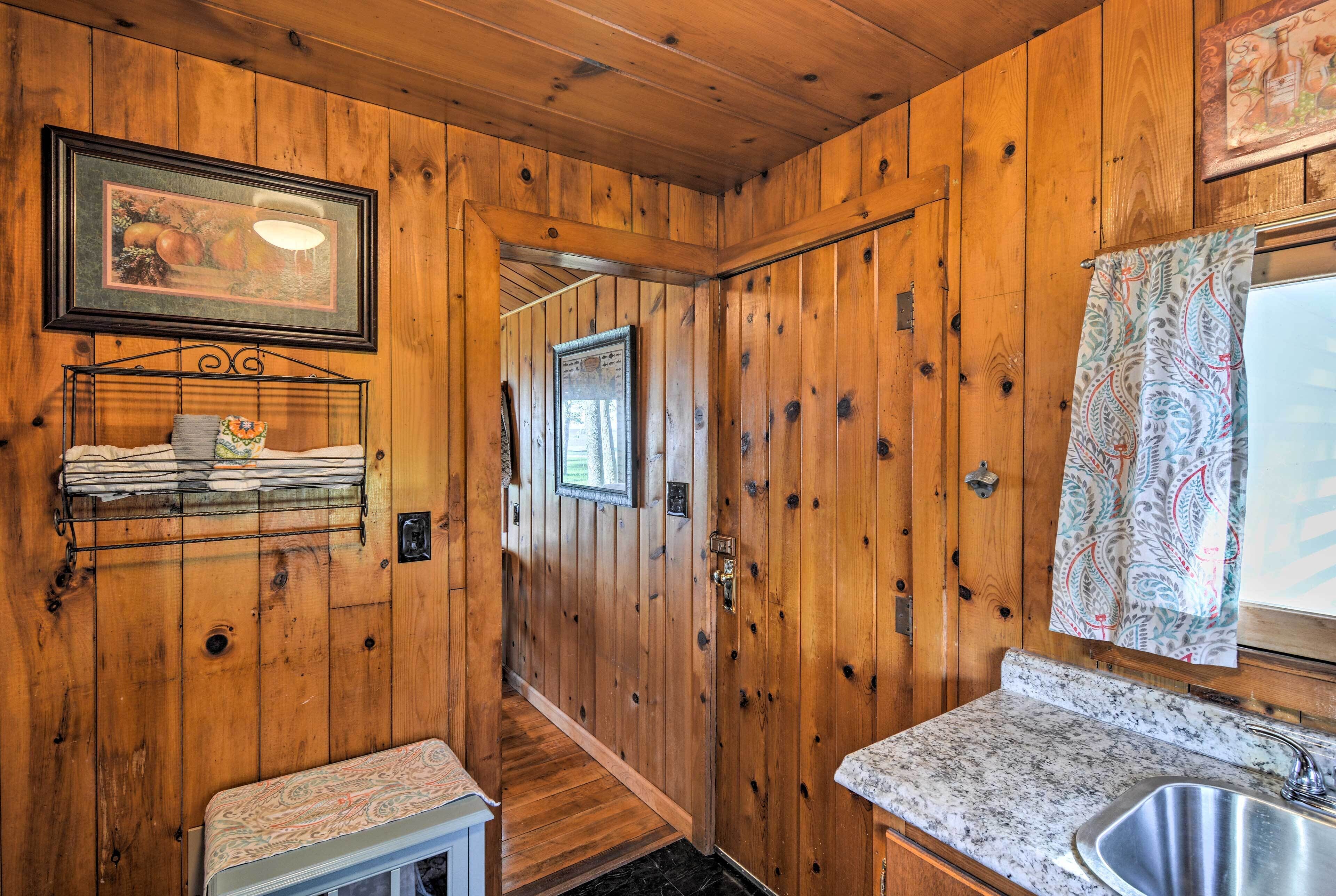 A wooden cabin interior with a kitchen area, including a sink, countertop, and a bench.