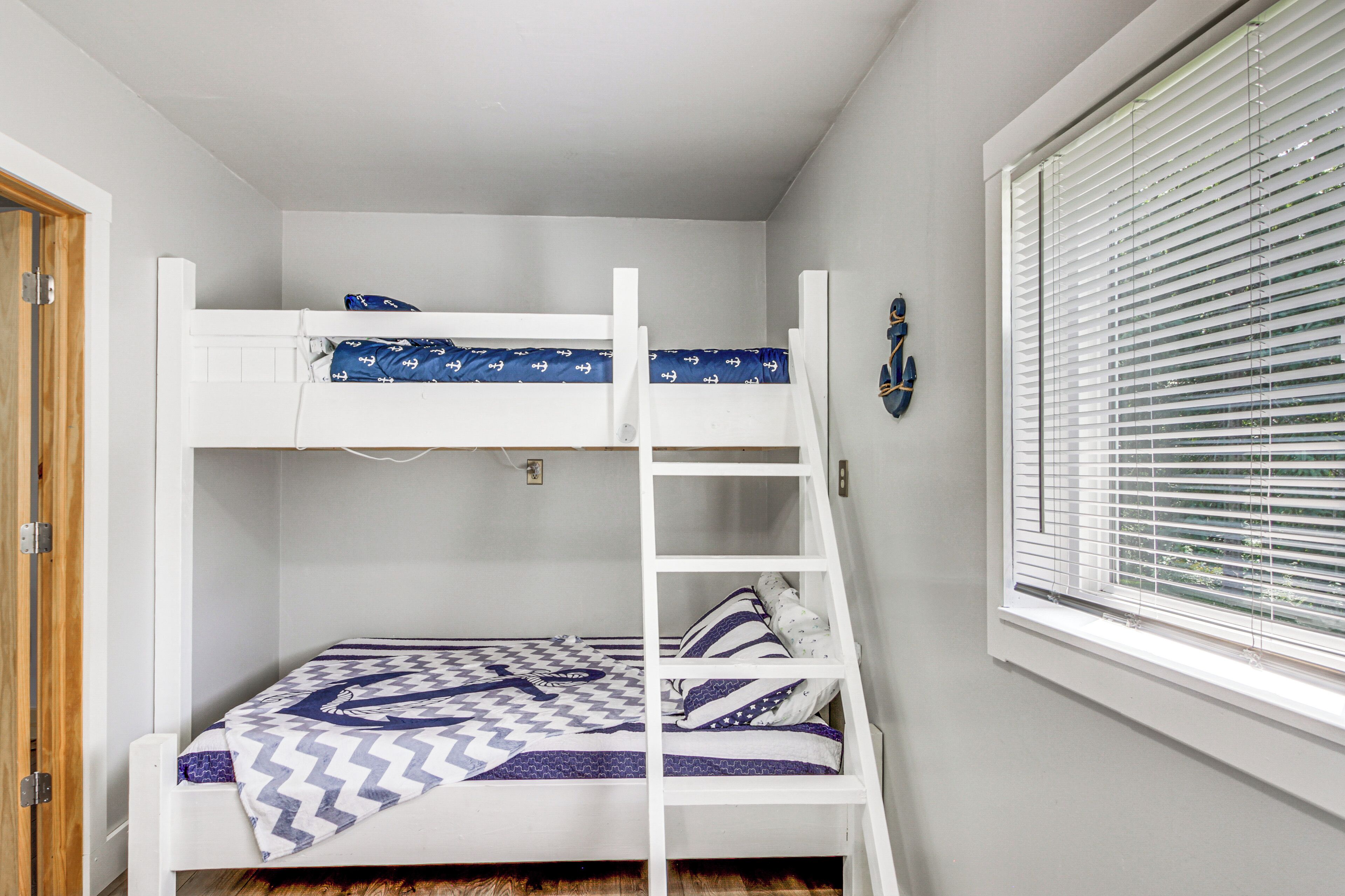 Une chambre avec un lit superposé, une fenêtre et une porte.