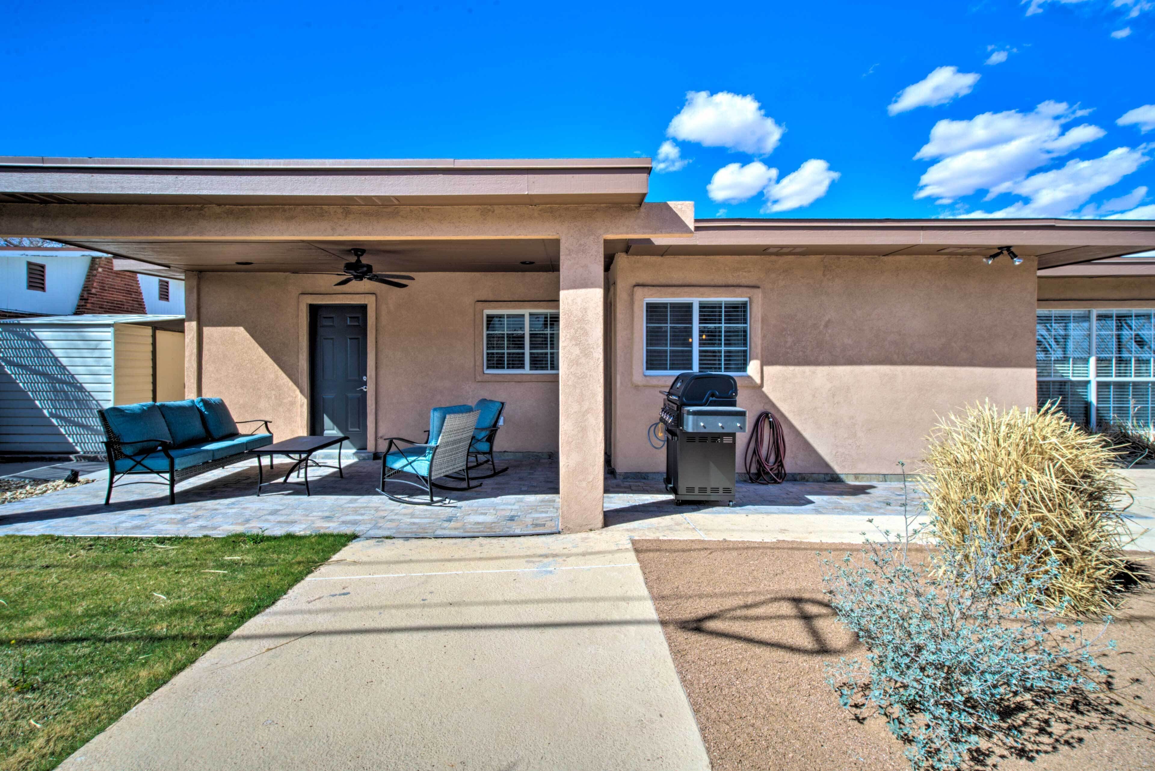 A residential house with a covered patio, outdoor seating, and a barbecue grill.