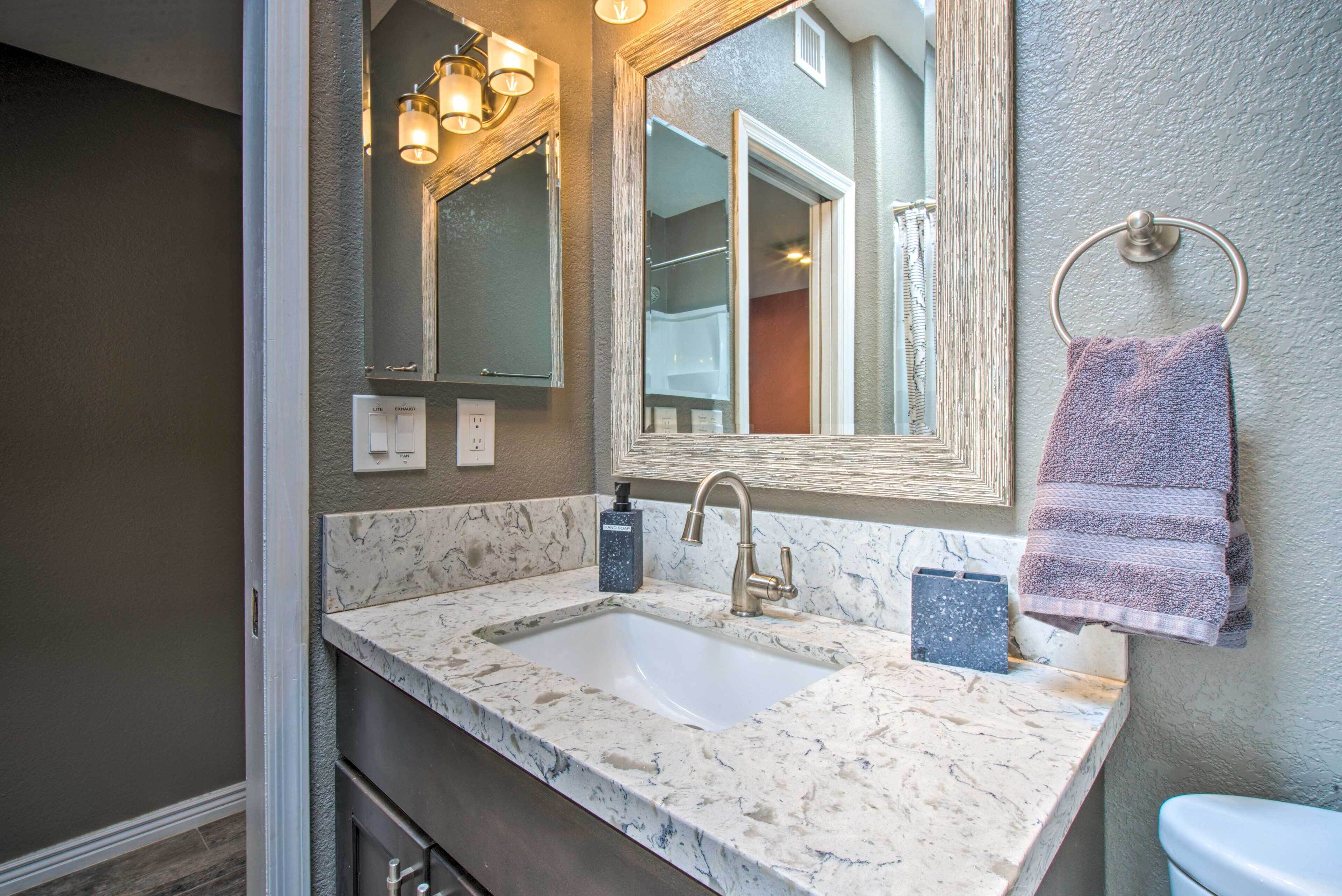A bathroom with a marble sink, a large mirror, and a towel rack.