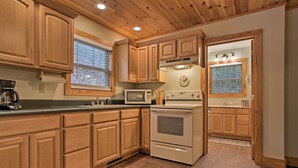 Une cuisine avec des meubles en bois, un four à micro-ondes, une cuisinière et une fenêtre avec des stores.