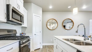 A modern kitchen with white cabinetry, stainless steel appliances, and a double sink. - Resort Pool & Hot Tub: Modern Condo in St George! (St. George)