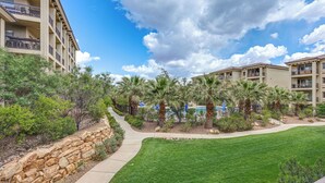 A resort with a pool area, palm trees, and a stone wall. - Resort Pool & Hot Tub: Modern Condo in St George! (St. George)
