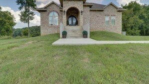A two-story house with a stone facade, a front entrance with steps, and a small front yard. - Mountain Home Gem on River! 0.4 Mi to Boat Launch (Mountain Home)