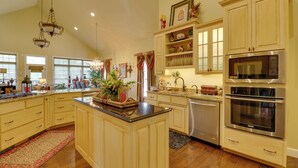 A spacious kitchen with wooden cabinets, a central island, stainless steel appliances, and decorative items. - Mountain Home Gem on River! 0.4 Mi to Boat Launch (Mountain Home)