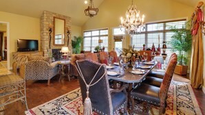 A spacious living room with a high ceiling, a fireplace, and a dining area with a long table and chairs. - Mountain Home Gem on River! 0.4 Mi to Boat Launch (Mountain Home)