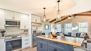 A modern kitchen with white cabinets, stainless steel appliances, and a wooden island. - Peaceful Brevard Mountain Cabin: Hike, Golf & Swim (Brevard)