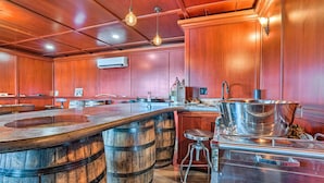 A bar area with wooden barrels, a stainless steel sink, and hanging light fixtures.