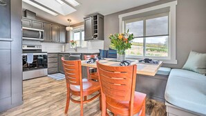 A modern kitchen with built-in appliances, a dining area with wooden chairs, and a large window offering a view.