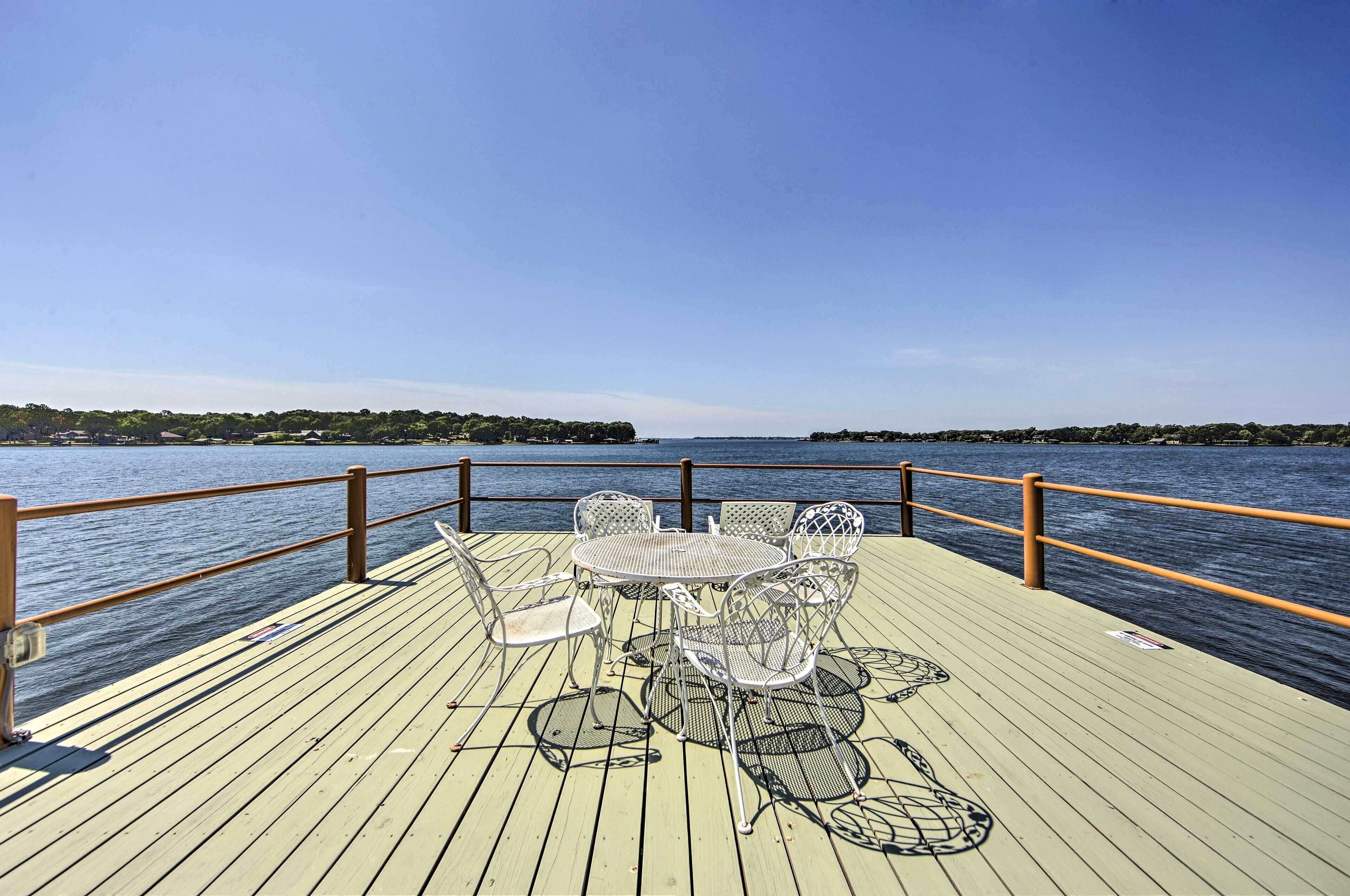 A wooden deck with a table and chairs overlooking a body of water.