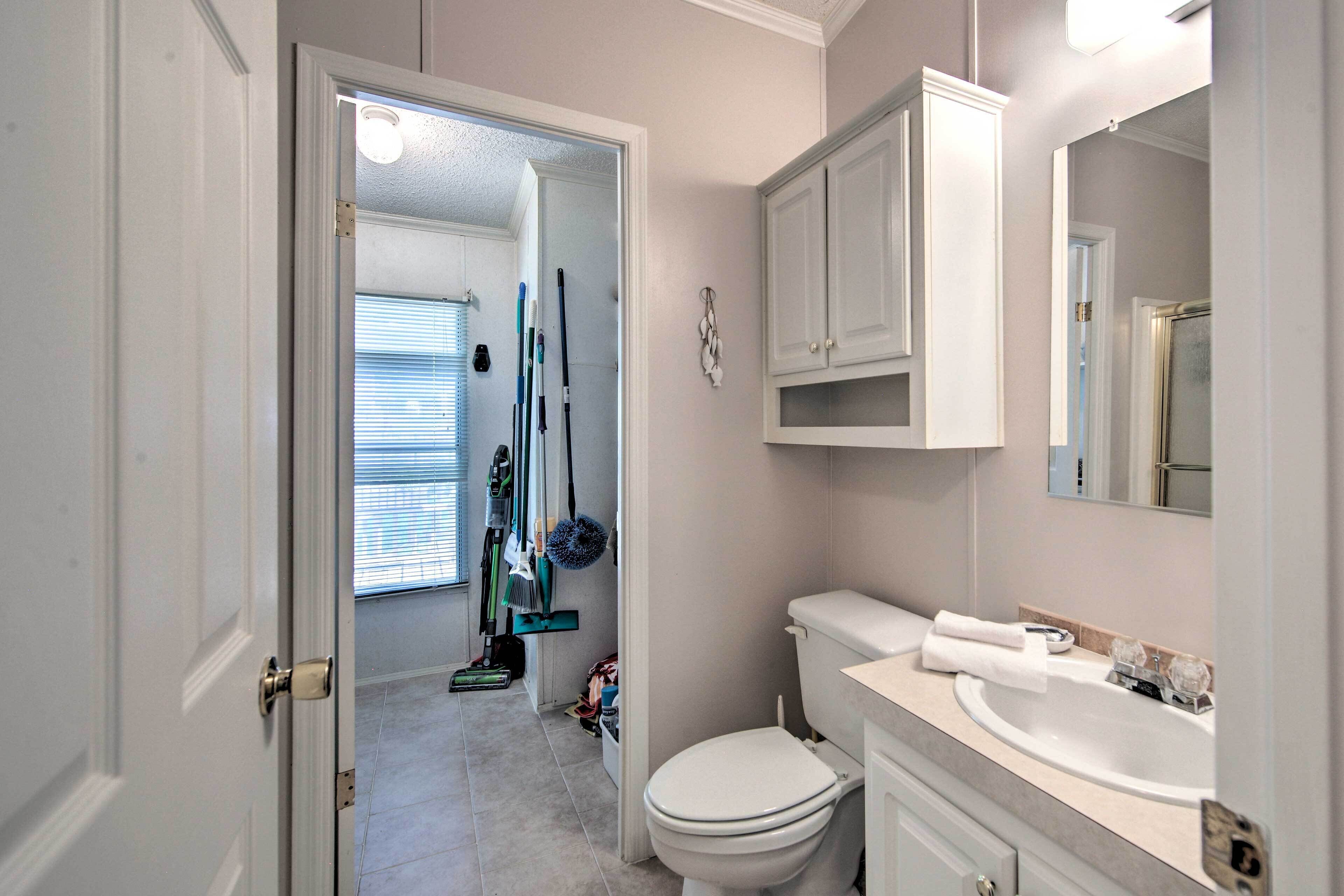 A bathroom with a toilet, sink, and cabinets. There is a door leading to another room.