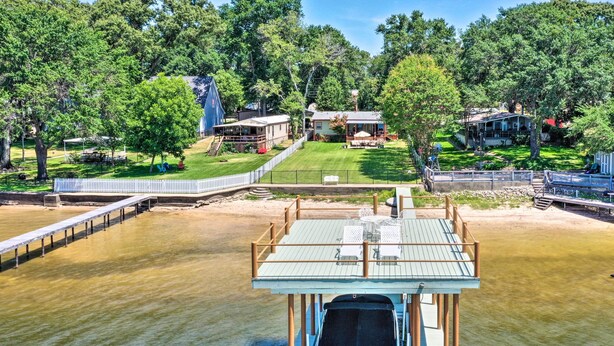 A boat docked at a pier with a view of a residential area and a large tree.