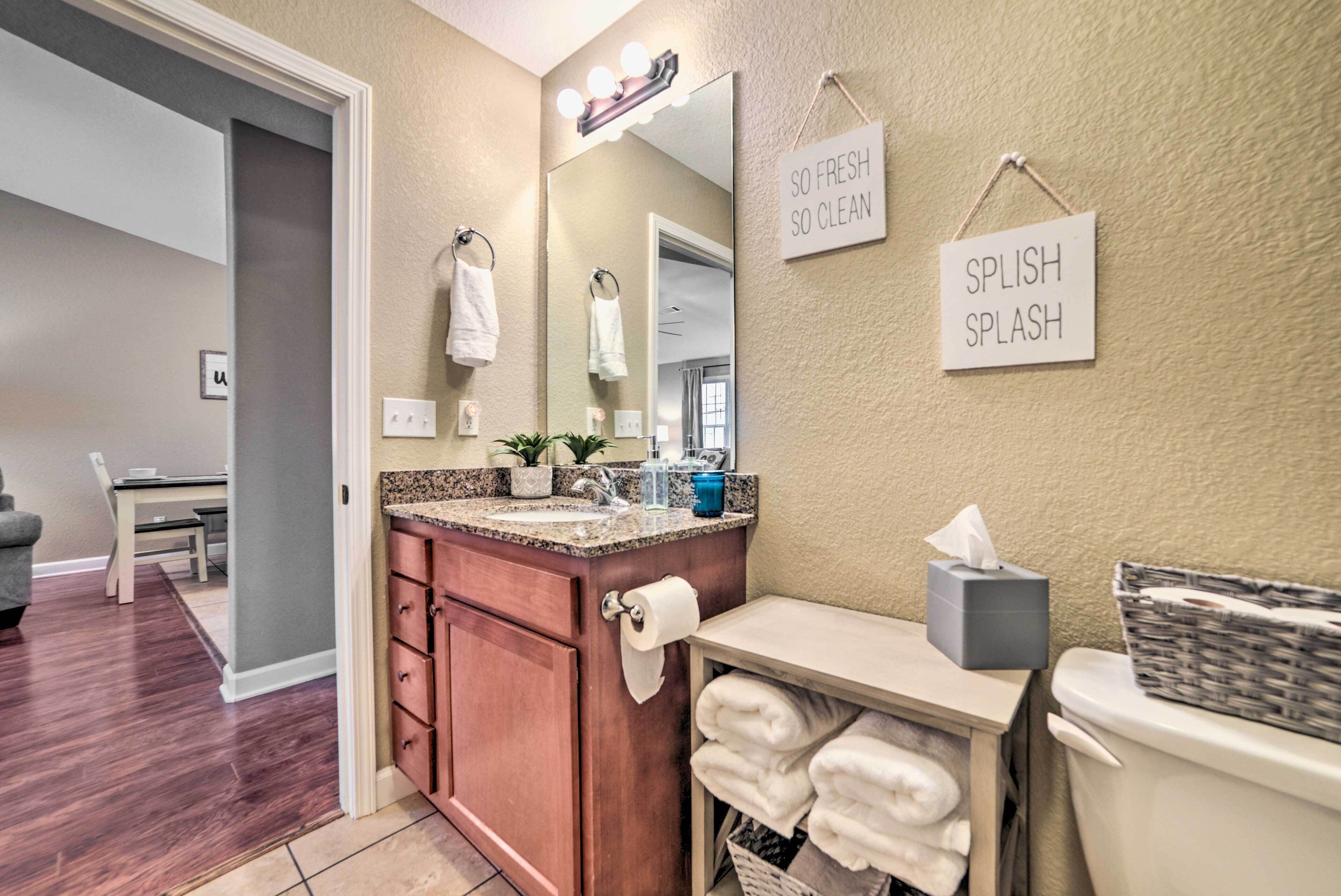 A bathroom with a vanity, mirror, towel rack, and signs saying "SO FRESH SO CLEAN" and "SPLISH SPLASH".