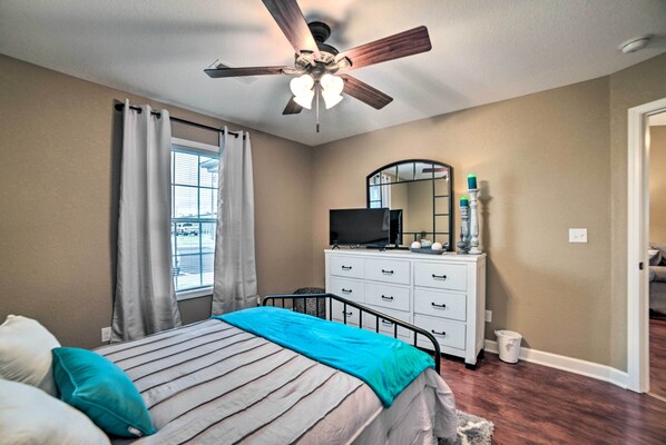 A bedroom with a bed, a ceiling fan, a dresser, a television, and a window with curtains. - Quaint Family Home Near Downtown Murray & MSU (Murray)