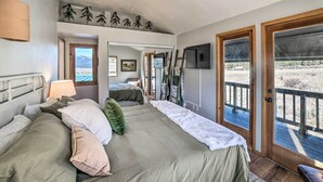 Een slaapkamer met een groot bed, een spiegel, een televisie en uitzicht op de omgeving.