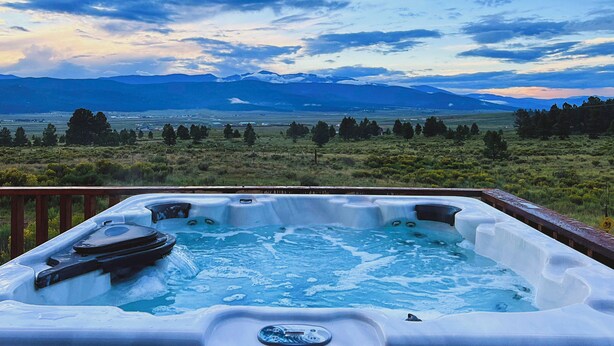 Een hottub met uitzicht op bergen en een grasachtig landschap.