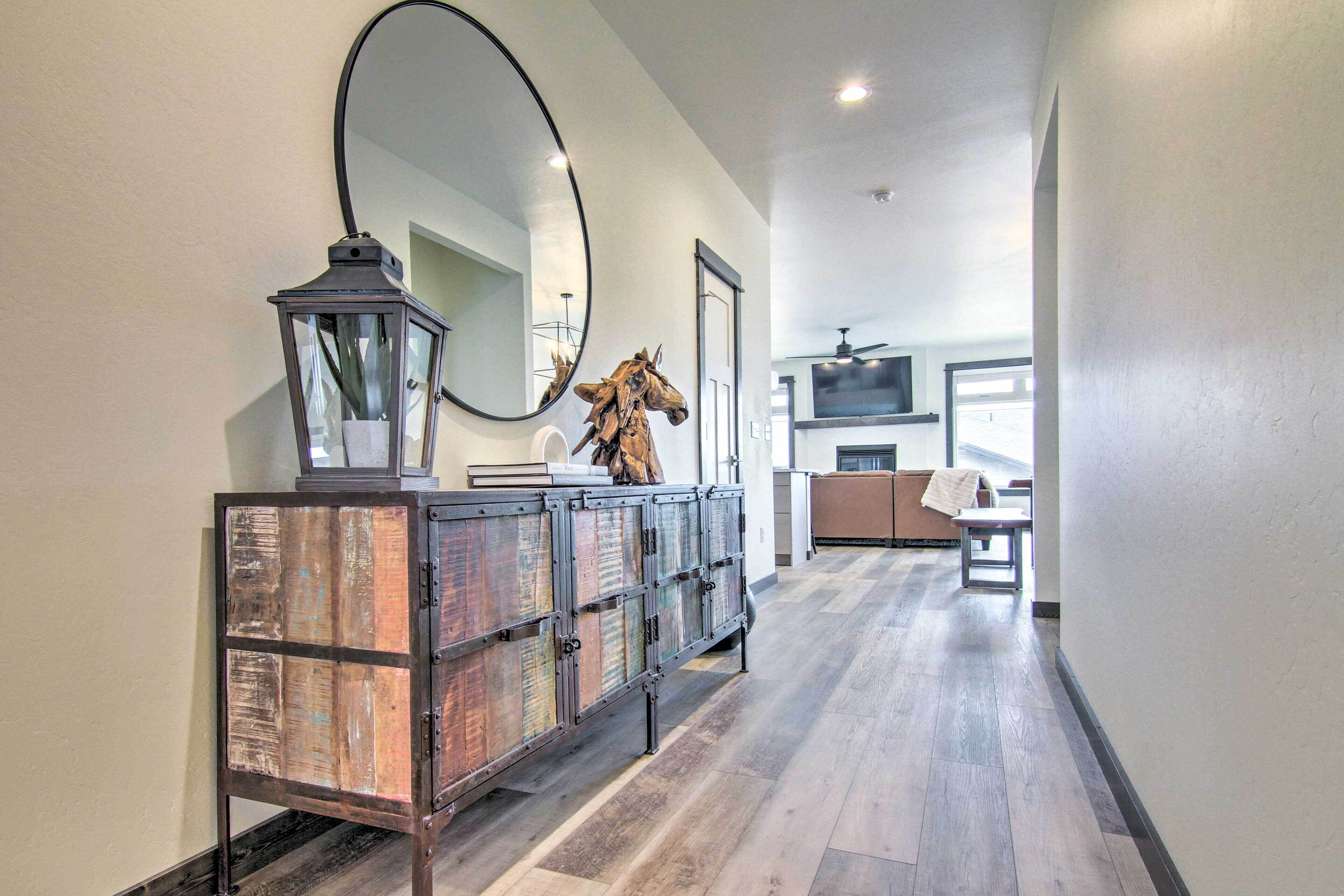 A hallway with a wooden cabinet, a mirror, and a mounted horse sculpture.
