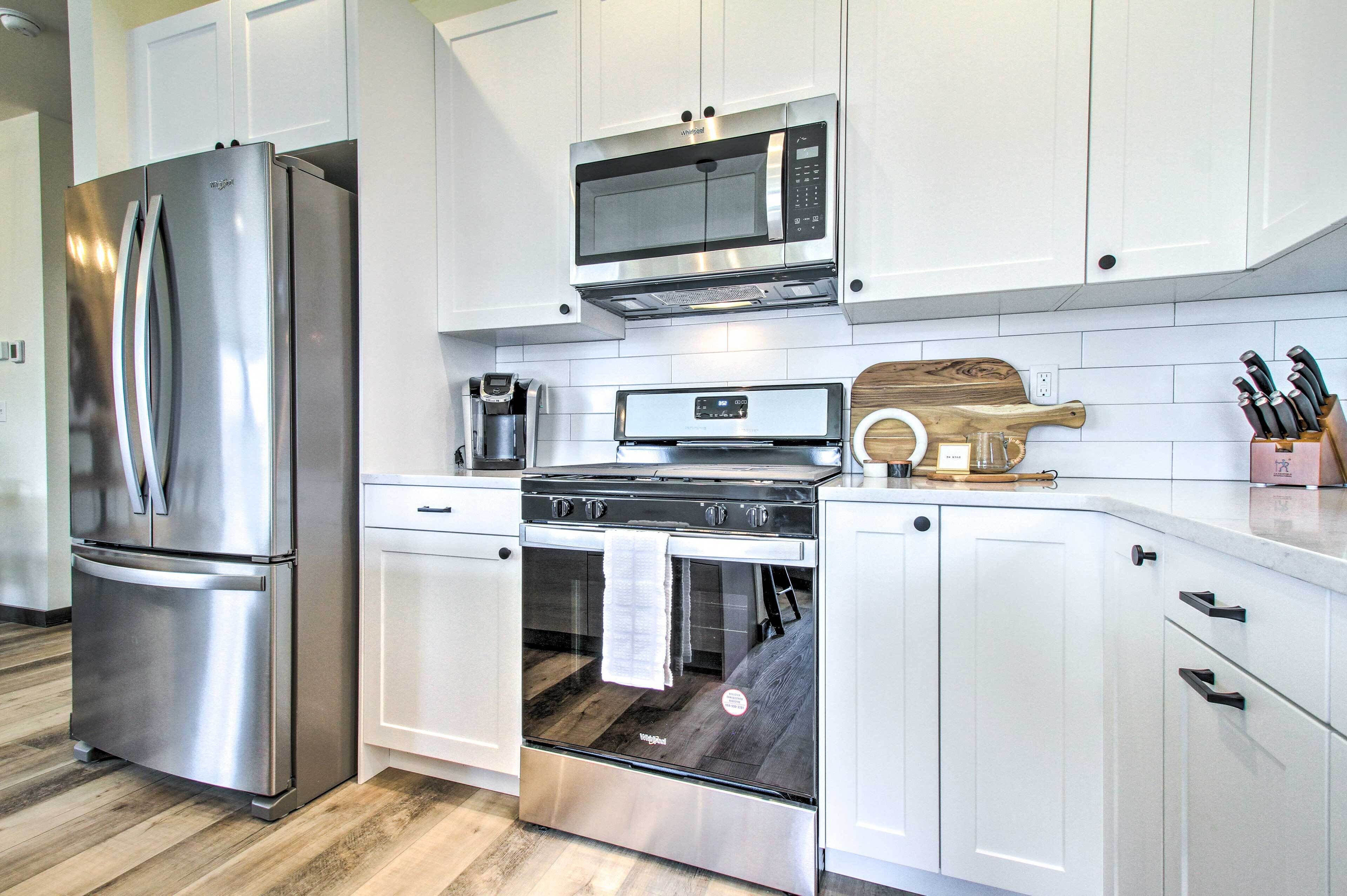 A modern kitchen with stainless steel appliances, white cabinetry, and a wooden countertop.