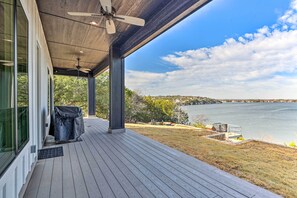 A covered outdoor area with a view of a lake, a barbecue setup, and a clear sky. - Entire Luxury Lake Granbury Cliffside Home w/ Deck (Granbury)