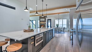 A modern kitchen with a large island, stainless steel appliances, and pendant lighting.