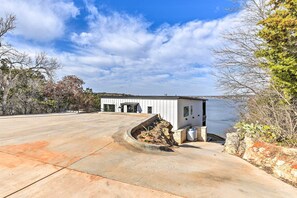 A building with a concrete driveway and a small garden area. - Entire Luxury Lake Granbury Cliffside Home w/ Deck (Granbury)