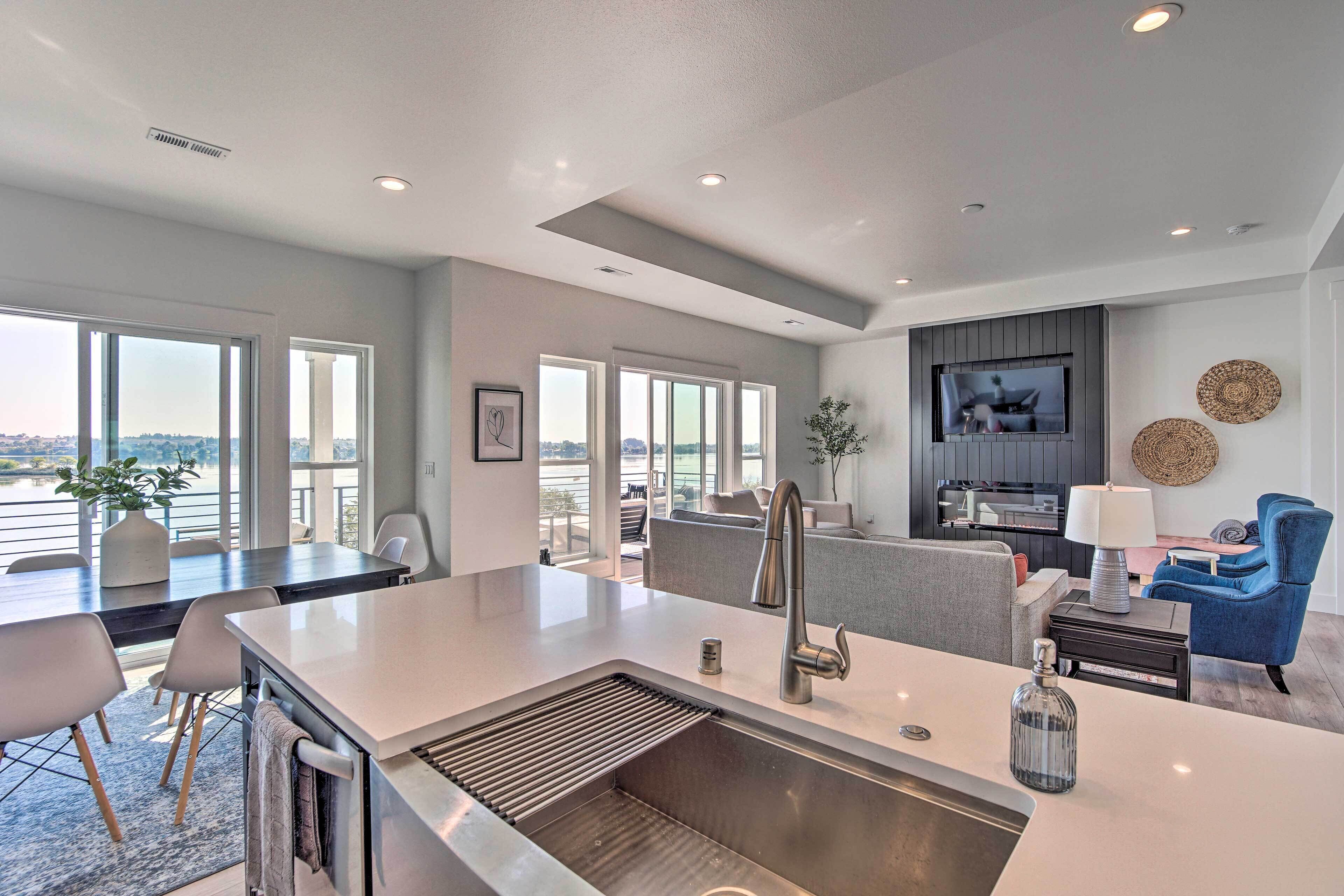 A modern kitchen with a large island, a dining area with a view, and a living space with a TV and seating.